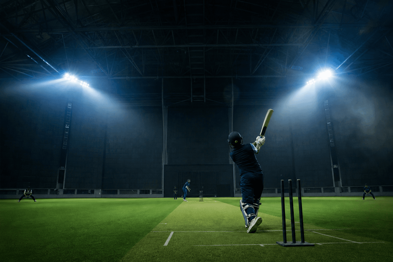 Indoor cricket stadium under dramatic floodlights